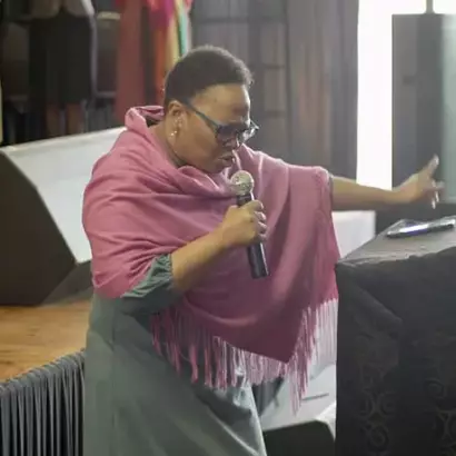 A woman praying into a microphone at a previous Glorious Worship gathering.