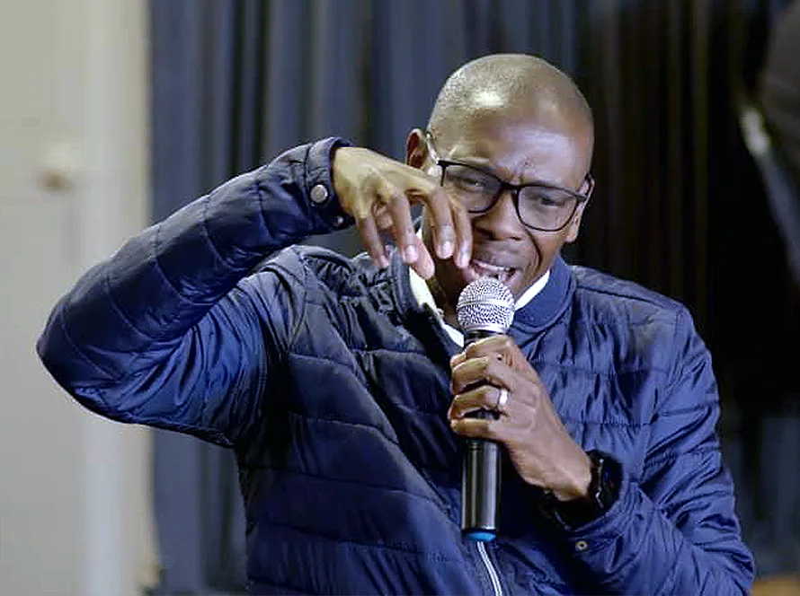 A man praying into a microphone at a Glorious Worship gathering.