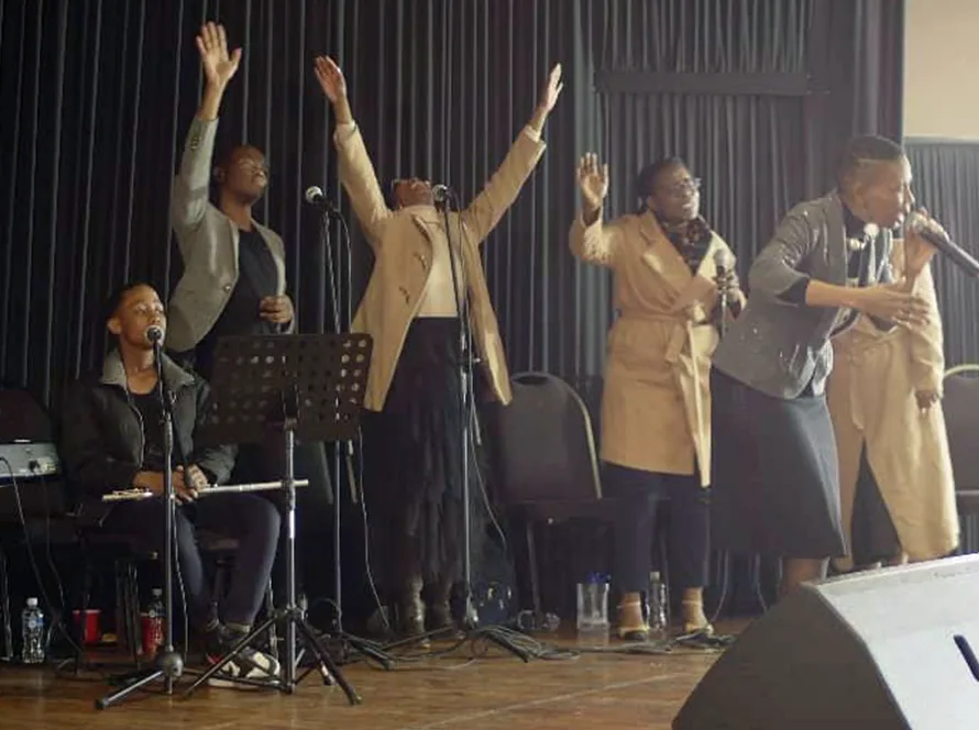 A worship team singing with hands raised at a previous Glorious Worship gathering.